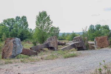 Metal elementlerle taştan yapılmış antik beton sütunlar. Ormanın arka planına karşı. Betonla çevre kirliliği. Beton bir köprü ormana giden yolu tıkıyor. Çevreye çöp atılmasını yasaklamak