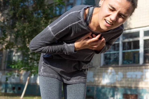while running, the young athlete had a heart attack. Disease of the heart and blood vessels. Acute coronary syndrome Young woman having heartache on grey background