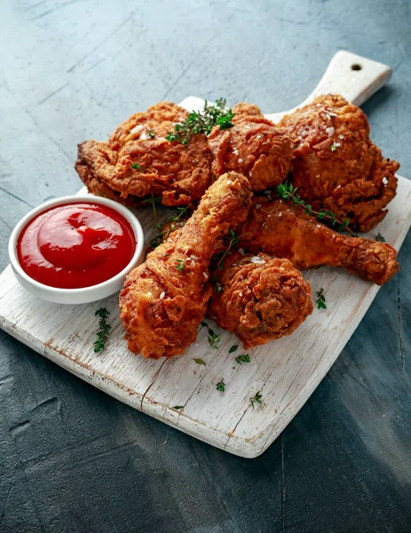 Kızarmış gevrek tavuk budu, beyaz kesme tahtası ketçap ve otlar ile uyluk