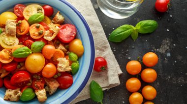 Kırmızı, sarı, turuncu kiraz domates, kapari, fesleğen ve ciabatta Panzanella domates salatası kruton. Yaz sağlıklı gıda.
