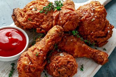 Kızarmış gevrek tavuk budu, beyaz kesme tahtası ketçap ve otlar ile uyluk