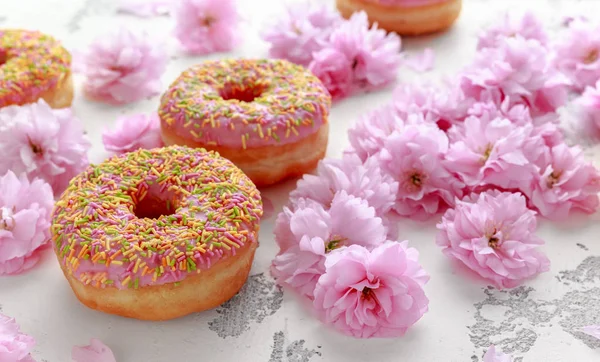 Rosado dulce Donut fresco decorado con flor de cerezo de floración japonesa — Foto de Stock