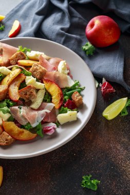 Taze ızgara şeftali salatası yeşil karışımı, peynir, jambon ve kızarmış ekmek parçaları ile