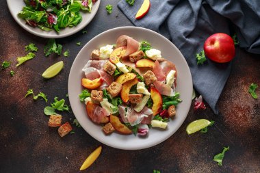 Taze ızgara şeftali salatası yeşil karışımı, peynir, jambon ve kızarmış ekmek parçaları ile