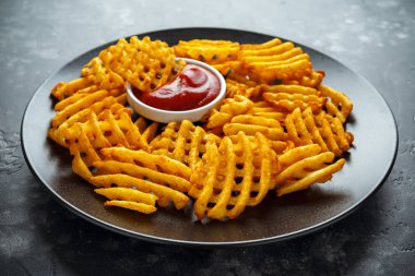Gevrek patates waffle yanında patates kızartması ketçap bir siyah plaka