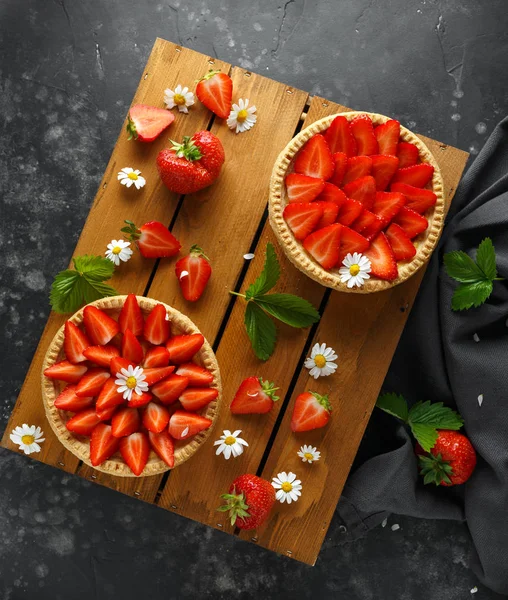 Nybakade Strawberry vaniljsås tårtor på träbricka med camomiles, sommar — Stockfoto