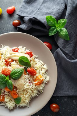 Buğulanmış morina balığı pirinç ve kiraz domates ve fesleğen otlar bir tabak içinde karıştırın