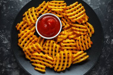 Gevrek patates waffle yanında patates kızartması ketçap bir siyah plaka