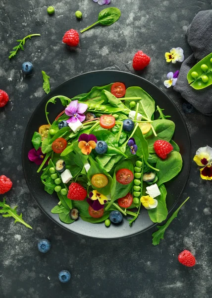 Sommarsallad med ätbara blommor, spenat, blåbär, hallon, sockerärtor, körsbär tomater och fetaost — Stockfoto