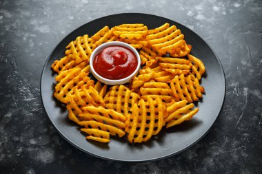 Gevrek patates waffle yanında patates kızartması ketçap bir siyah plaka