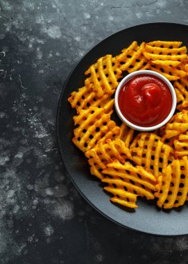 Gevrek patates waffle yanında patates kızartması ketçap bir siyah plaka