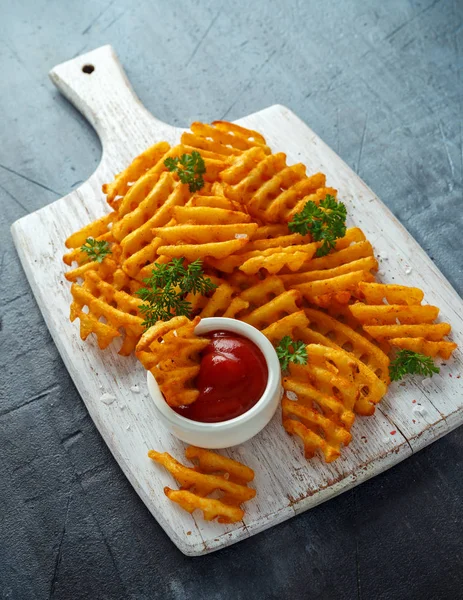 Crispy Potato Waffles Fries with Ketchup on white wooden board