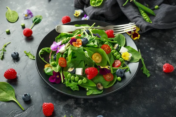 Літній салат з їстівними квітами, шпинатом, чорницею, малиною, солодким горохом, вишневими томатами та сиром фета — стокове фото