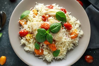 Buğulanmış morina balığı pirinç ve kiraz domates ve fesleğen otlar bir tabak içinde karıştırın