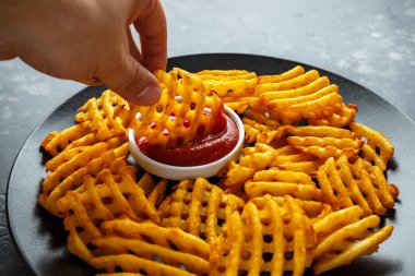 Gevrek patates waffle yanında patates kızartması ketçap bir siyah plaka