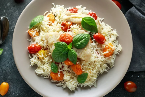 Buğulanmış morina balığı pirinç ve kiraz domates ve fesleğen otlar bir tabak içinde karıştırın