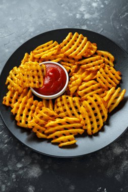 Gevrek patates waffle yanında patates kızartması ketçap bir siyah plaka