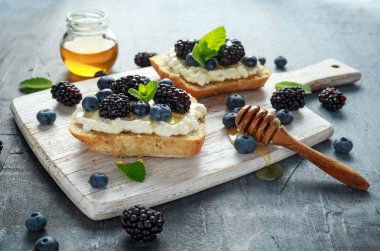 Taze tatlı böğürtlen, yaban mersini bruschetta, süzme peynir, bir beyaz tahta bal tost.