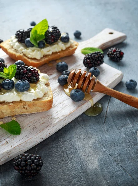 Färska söta Blackberry, blåbär bruschetta, toast med keso, honung i en vit tavla. — Stockfoto