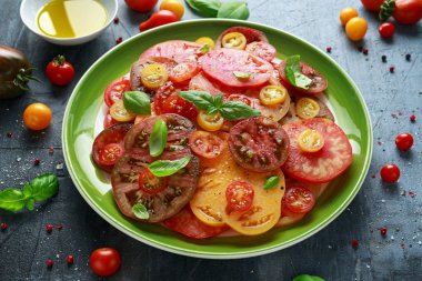 Renkli domates salatası Hatıra, armut şeklinde, sığır eti kalp, tigerella, yeşil bir tabak içinde brandywine, kiraz, siyah domates. sağlıklı gıda