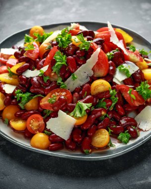 Healthy Red beans and mix of organic red and yellow pear shaped, beef heart and cherry tomatoes salad with picorino romano cheese shavings topped with parsley clipart
