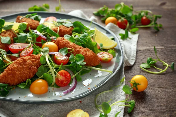 Fresh salad with chicken nuggets, cherry tomatoes and green vegetables in a rustic wooden table — Stock Photo, Image