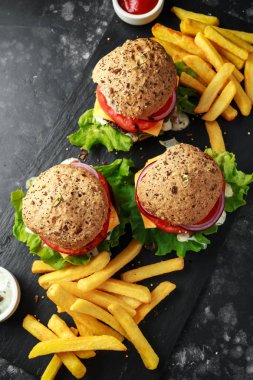 sığır eti burger marul, Yunan yoğurt sosu, biftek domates, kırmızı soğan halkaları ve eritilmiş peynir rustik bir sayaçta patates kızartması ile servis ızgara