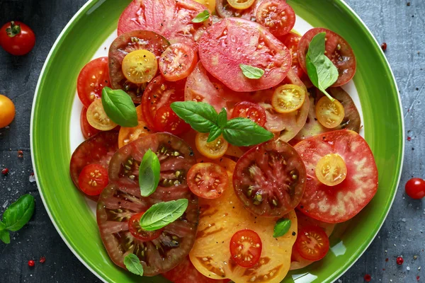 Colorful Tomato Salad with heirloom, pear shaped, beef heart, tigerella, brandywine, cherry, black tomatoes in a green plate. healthy food — Stock Photo, Image