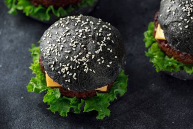 Peynir, et ve yeşil salata ile siyah Burger bırakıyor. Ev yapımı çizburger