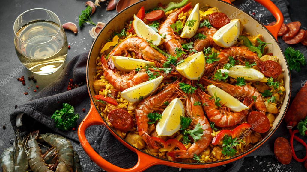 Paella tradicional en la sartén con pollo, gambas, chorizo picante