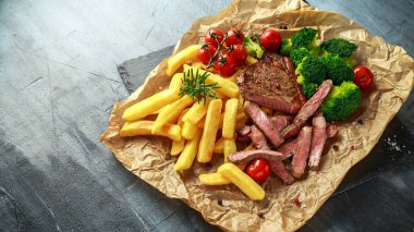 Patates kızartması, brokoli ve kiraz domates buruşuk Kağıt üzerinde ızgara sığır filetosu biftek