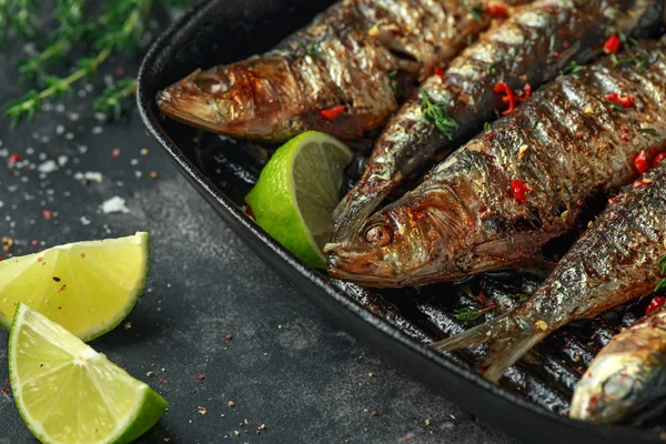 Gegrillte Sardinen mit Thymian, Chili und Limettenkeilen auf gusseiserner Pfanne — Stockfoto