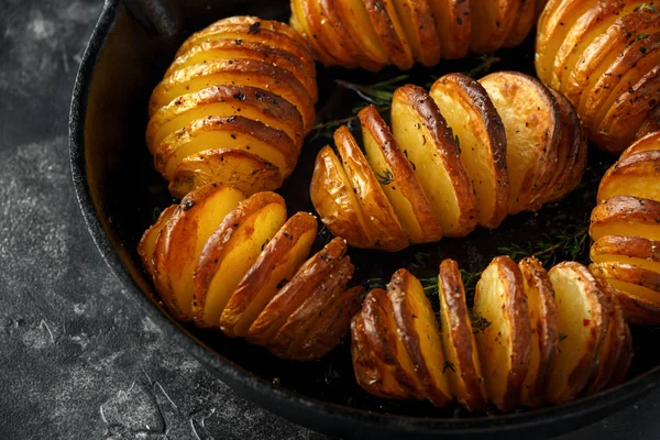 Batatas assadas Hasselback servidas em panela de ferro fundido com sal, pimenta e ervas — Fotografia de Stock