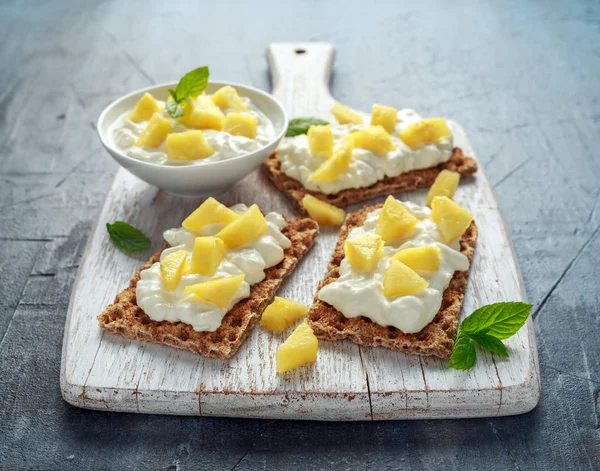 Tostadas caseras de pan crujiente con queso Cottage y piña sobre tabla de madera blanca . —  Fotos de Stock