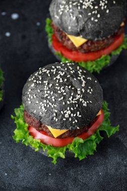 Peynir, Dana eti, domates ve yeşil salata ile siyah Burger bırakıyor. Ev yapımı çizburger