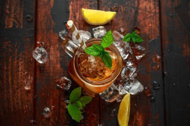 Cam, rustik ahşap zemin üzerine nane ve limon dilimleri ile çay buz