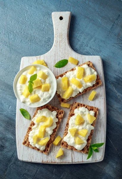 Tostadas caseras de pan crujiente con queso Cottage y piña sobre tabla de madera blanca . —  Fotos de Stock