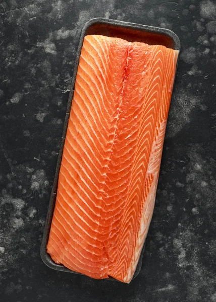 Raw filet z lososa v zásobníku na tmavé kamenné pozadí — Stock fotografie