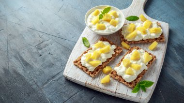 Beyaz ahşap tahta üzerinde süzme peynir ve ananas ile ev yapımı Crispbread ekmeği.