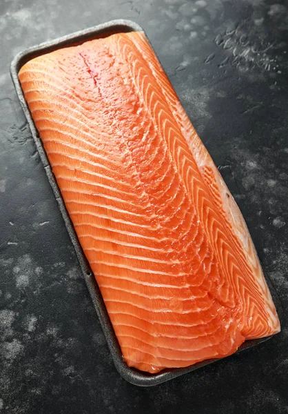 Raw salmon fillet in tray on dark stone background — Stock Photo, Image