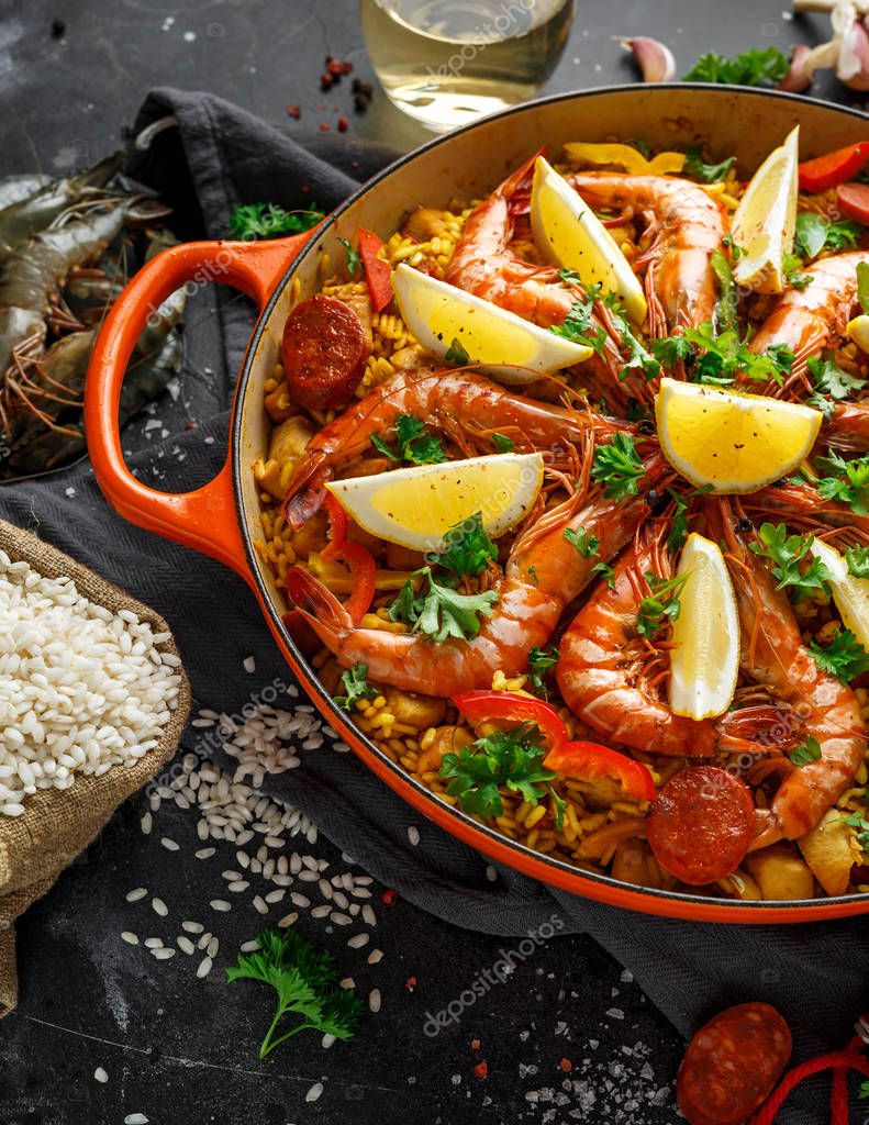 Paella tradicional en la sartén con pollo, gambas, chorizo picante