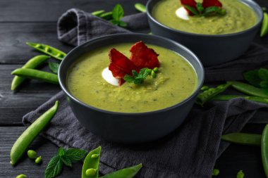 Tatlı bezelye, pırasa ve nane sıcak çorba gevrek domuz pastırması ve dolop yoğurt ile tepesinde.