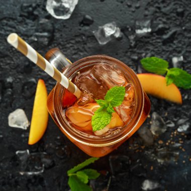 Şeftalili buzlu çay nane rustik siyah arka plan üzerine cam ile. yaz meyve soğuk içecekler.