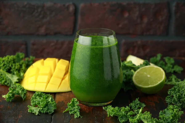 Zelené smoothie s kale a mango na dřevěný stůl — Stock fotografie