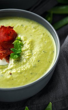 Tatlı bezelye, pırasa ve nane sıcak çorba gevrek domuz pastırması ve dolop yoğurt ile tepesinde.