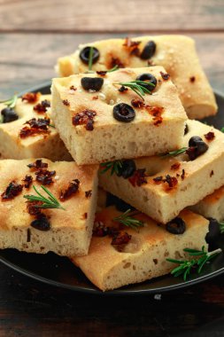 Ev yapımı FOCACCE çeşitleri güneş ile kurutulmuş domates, siyah zeytin ve biberiye.