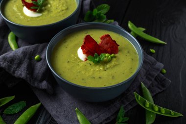 Tatlı bezelye, pırasa ve nane sıcak çorba gevrek domuz pastırması ve dolop yoğurt ile tepesinde.