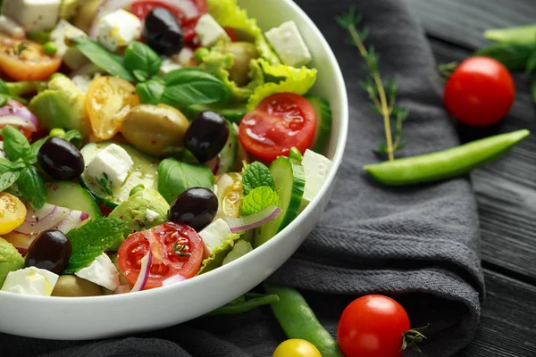 Salada saudável de baixas calorias com alface, tomate, abacate, queijo feta, cebola vermelha, pepino, ervilhas doces, azeitonas, tomilho, hortelã e manjericão . — Fotografia de Stock