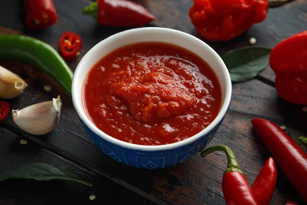 Spicy hot sweet chili sauce with mix of chilli pepper, garlic and tomatoes on rustic wooden background — Stock Photo, Image