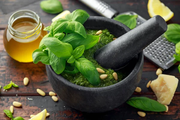 Green Basil Pesto em argamassa de mármore com queijo parmesão, pinhões, alho e limão . — Fotografia de Stock